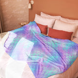 The blanket spread across the foot or center of a bed to demonstrate coverage and use as a bedding layer.